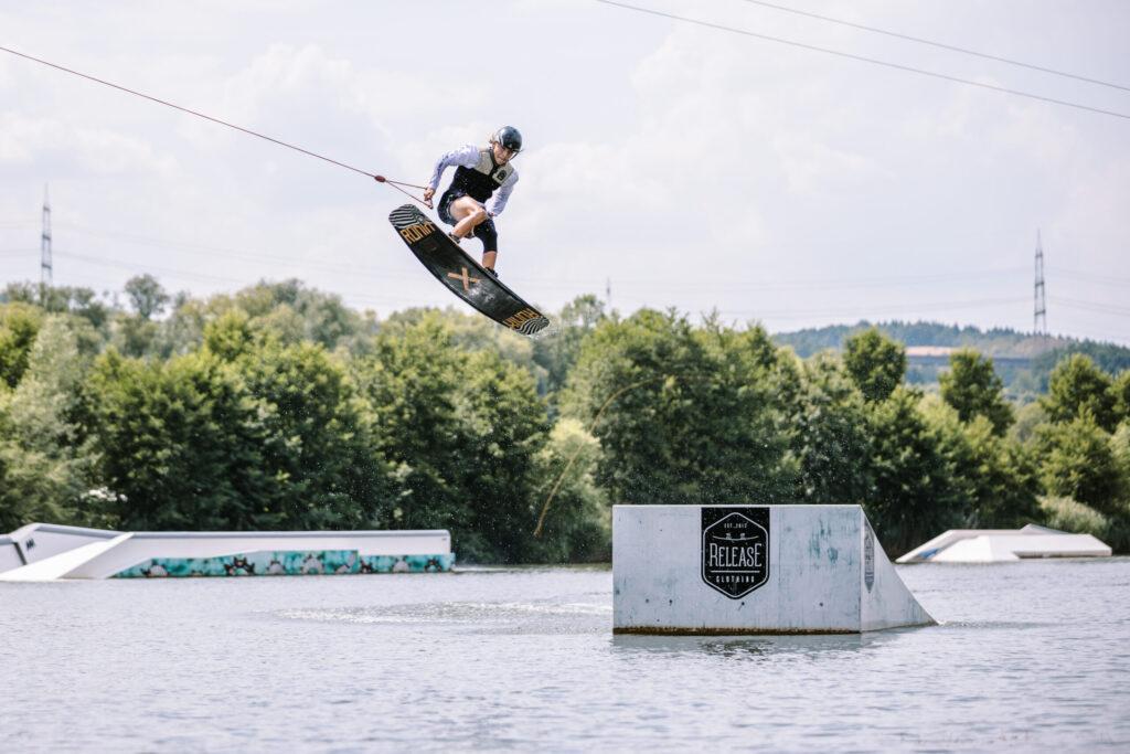 Ein junger Wakeboarder springt über eine Kicker